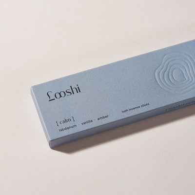 Powder blue box of Looshi Calm incense sticks on a cream surface, featuring labdanum, vanilla and amber fragrances