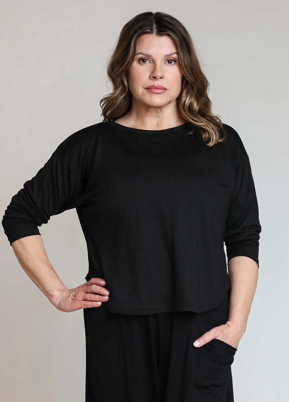 Woman wearing a black merino wool lounge top designed for recovery, travel, layering, and everyday wear.