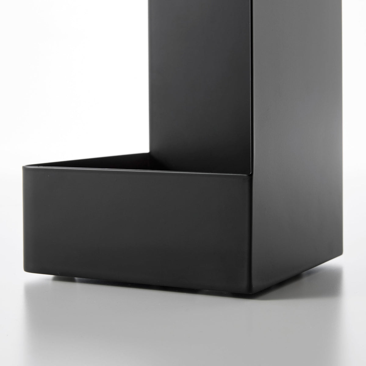 Detail of the black Yamazaki Home Rolling Bathroom Organizer - Steel base, showing the deep lower tray, raised front wall and smooth vertical side panel.