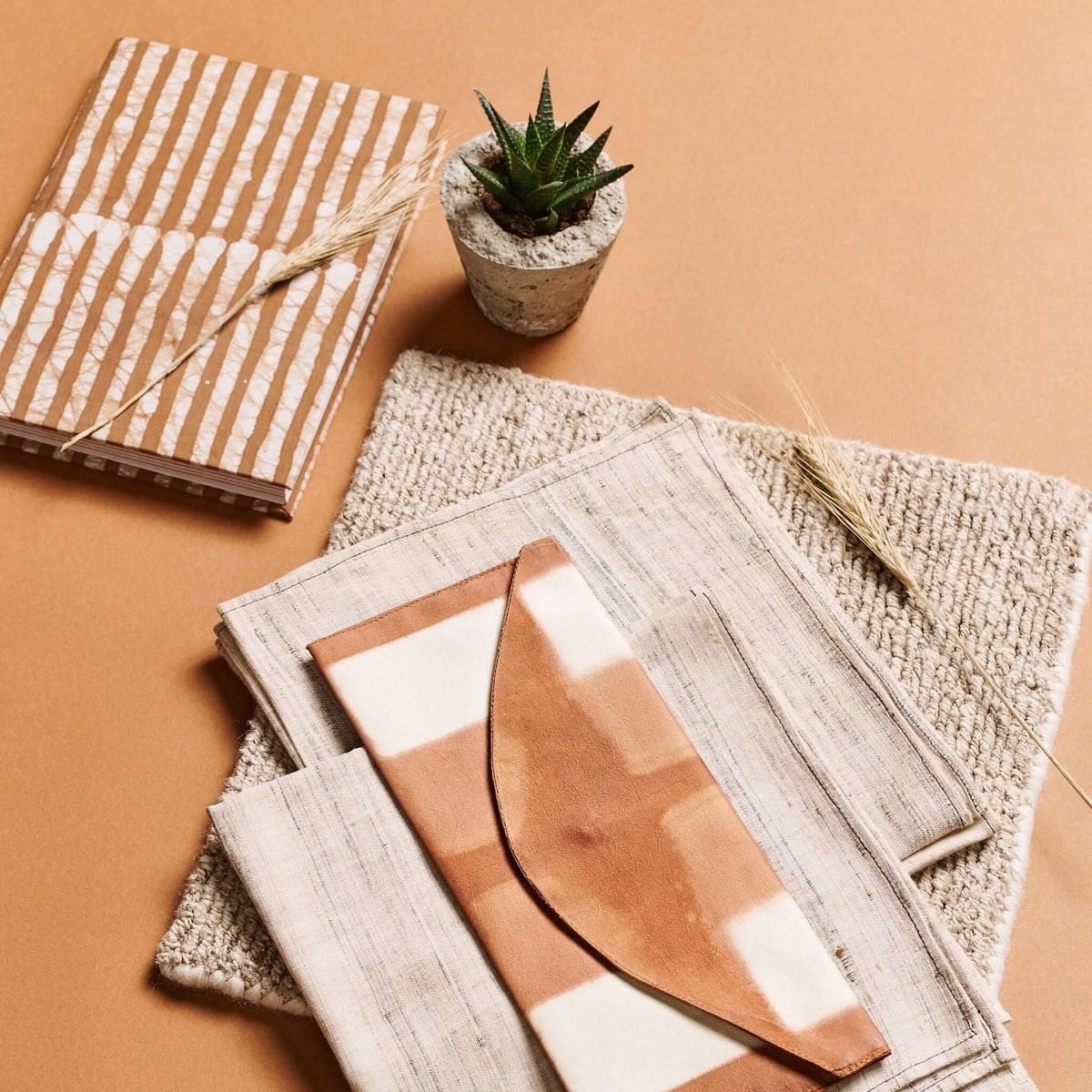 Overhead view of the Oak Brown journal with art prints, textured handmade paper and a small potted succulent