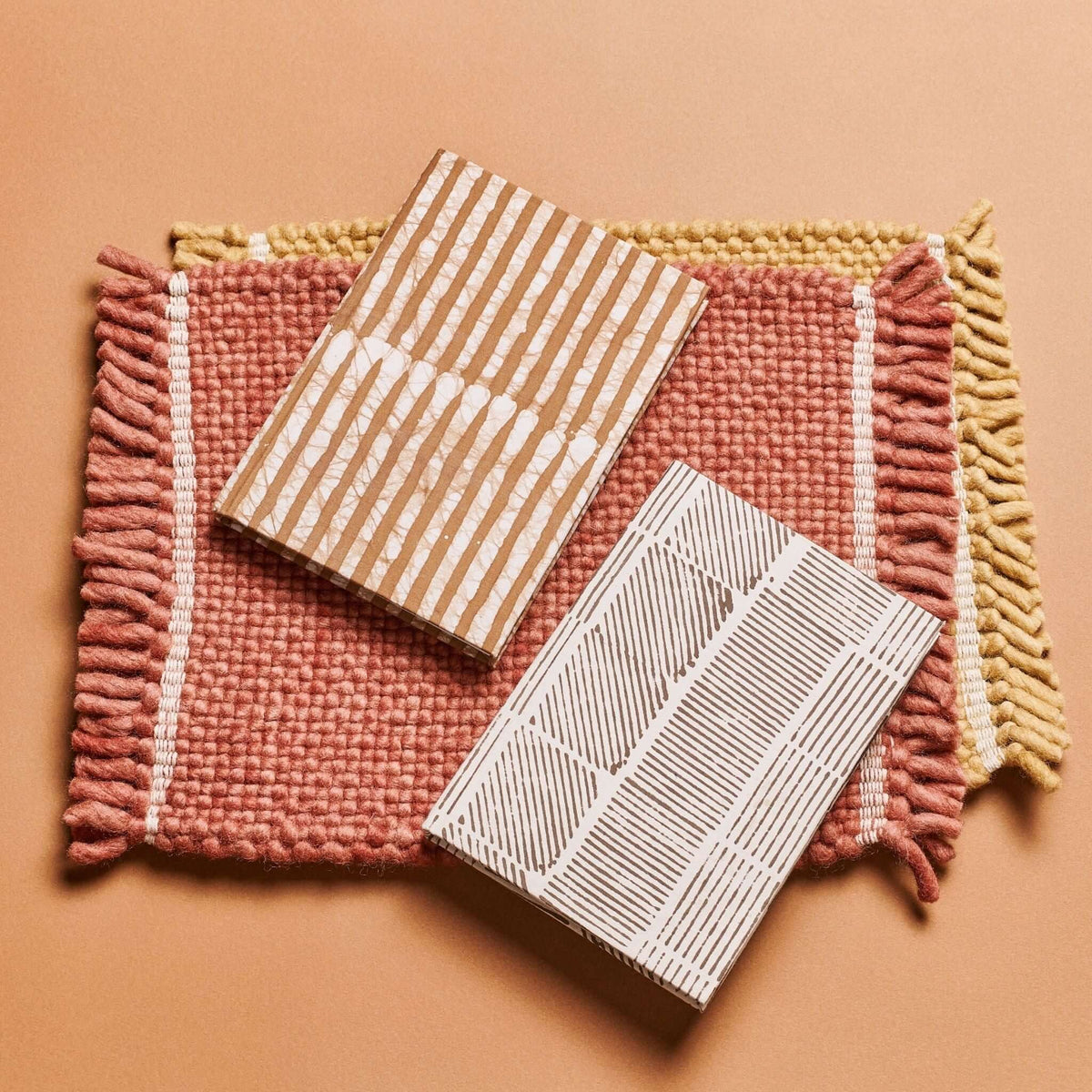 Oak Brown and white color variations of the handmade journal arranged on a rust-colored woven mat