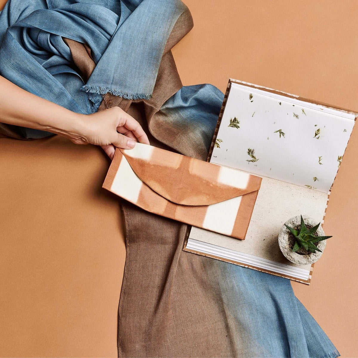 Person holding the open Oak Brown journal on their lap, displaying handmade pages, natural flecks and an inserted art print