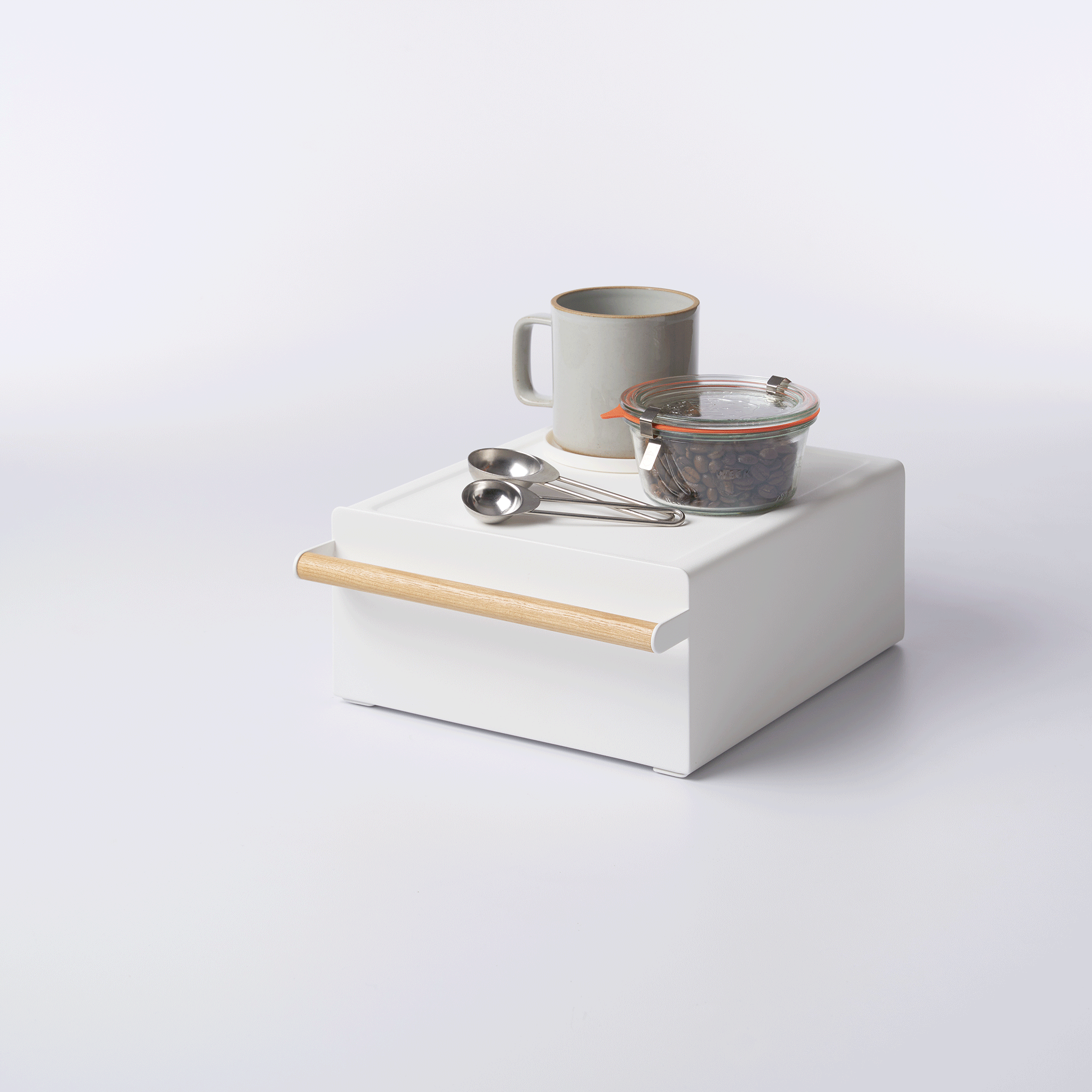 Yamazaki Home Countertop Rack with Drawer - Steel + Wood supporting a white gooseneck kettle, with the drawer open to reveal orange and green packets on a pale background.