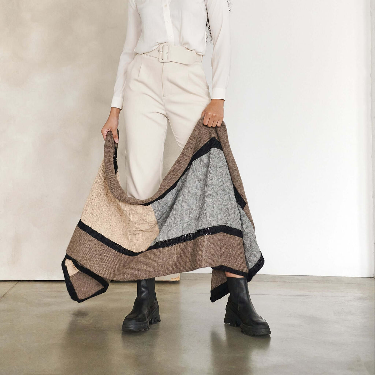 Full-length view of a woman carrying the open blanket beside her, showing its length and drape.