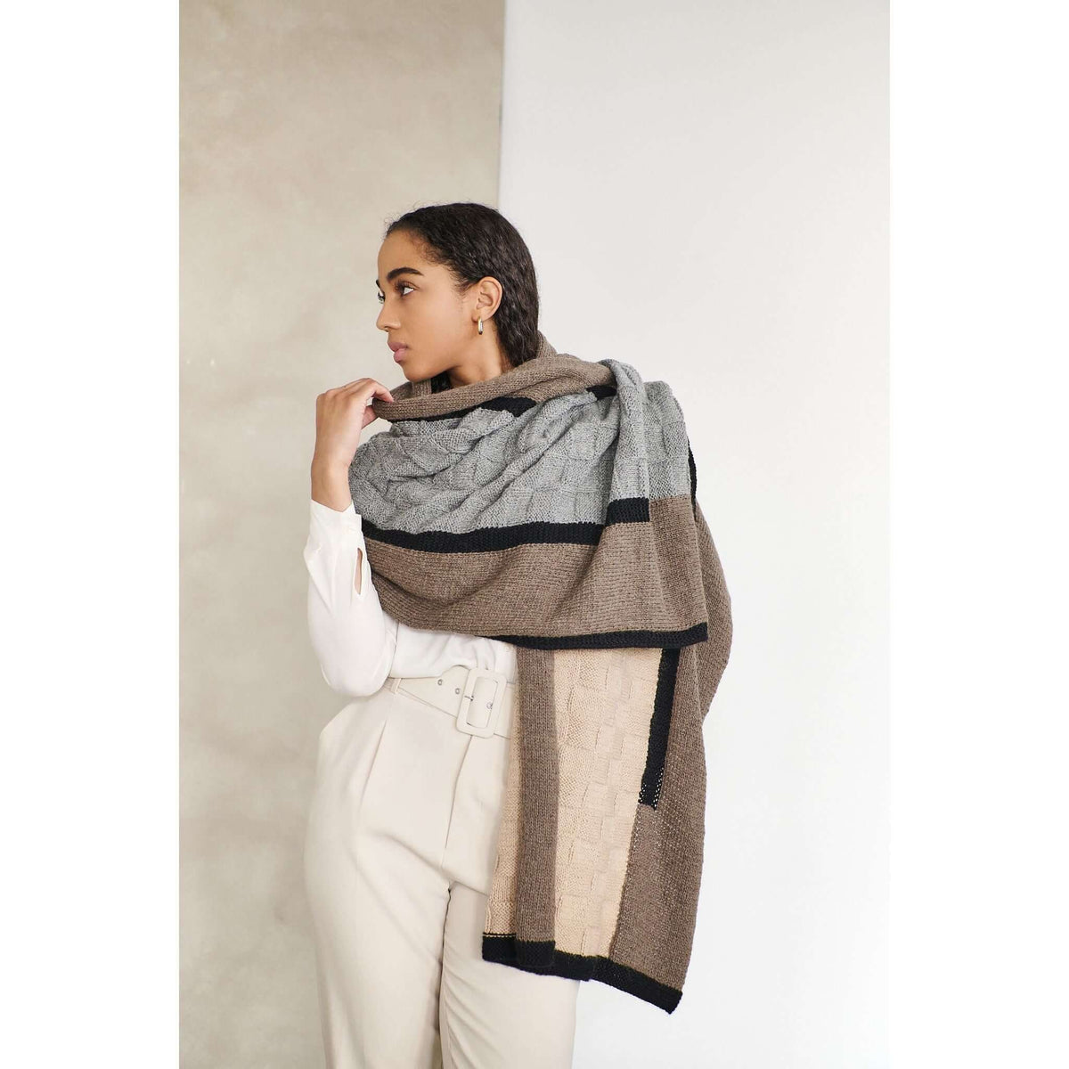 Woman wearing the alpaca blanket as a shawl over a white outfit.