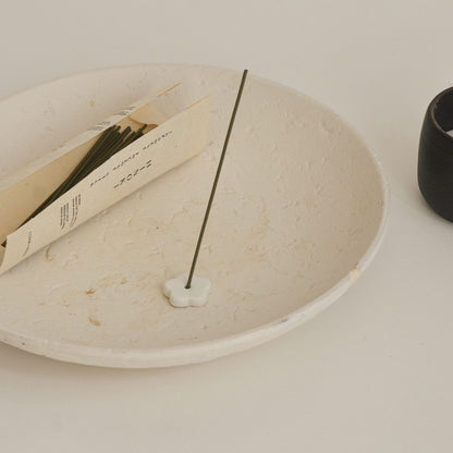 Incense stick on a white plate with a minimal background
