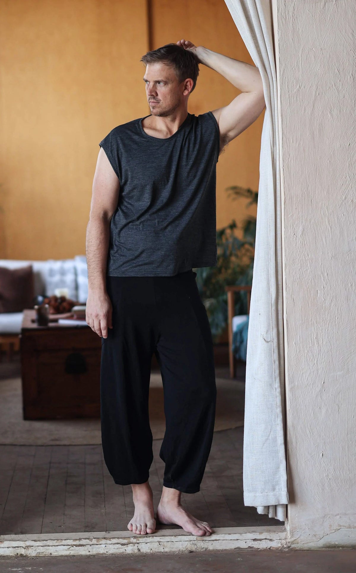 Man wearing black merino wool lounge pants and a matching merino tee, designed for post-sauna recovery, travel, and everyday comfort.