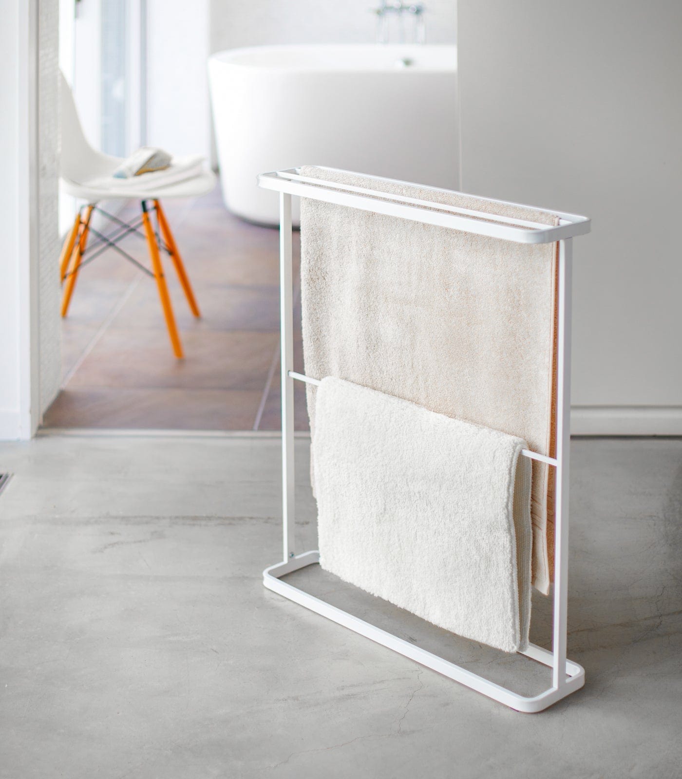 White towel rack with folded towels in a minimalistic bathroom setting. Bath Towel Hanger (30" H)  - Steel
