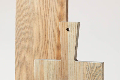 Close-up of overlapping pale wood Pantry Cutting Boards, highlighting their paddle handles, hanging holes, squared edges, and prominent natural grain.