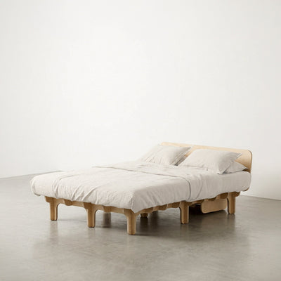 Wide DOVID natural wood bed frame with white bedding, two pillows, a low curved headboard and evenly spaced rounded legs