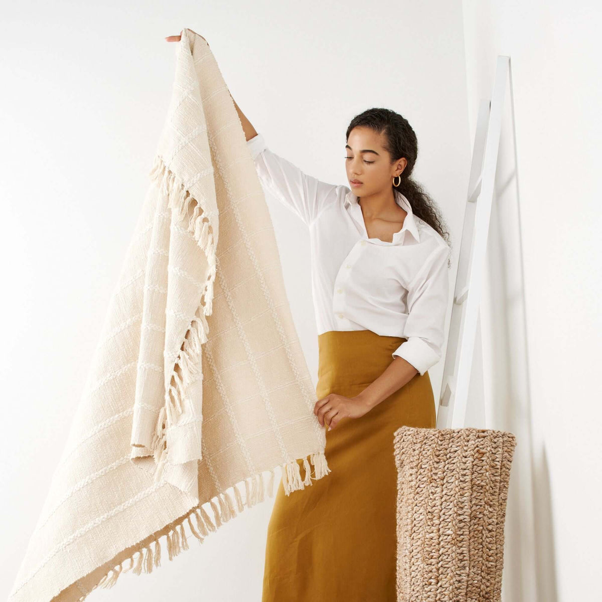 Woman holding the Sea Shell White handloom throw open to display its full size, textured checks and fringed edges