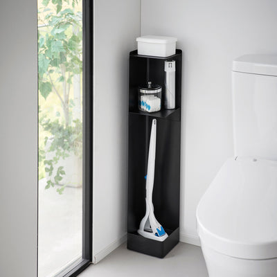 Black Yamazaki Home Rolling Bathroom Organizer - Steel beside a white toilet and window, holding a white tissue box, small bathroom supplies and long white cleaning tools.