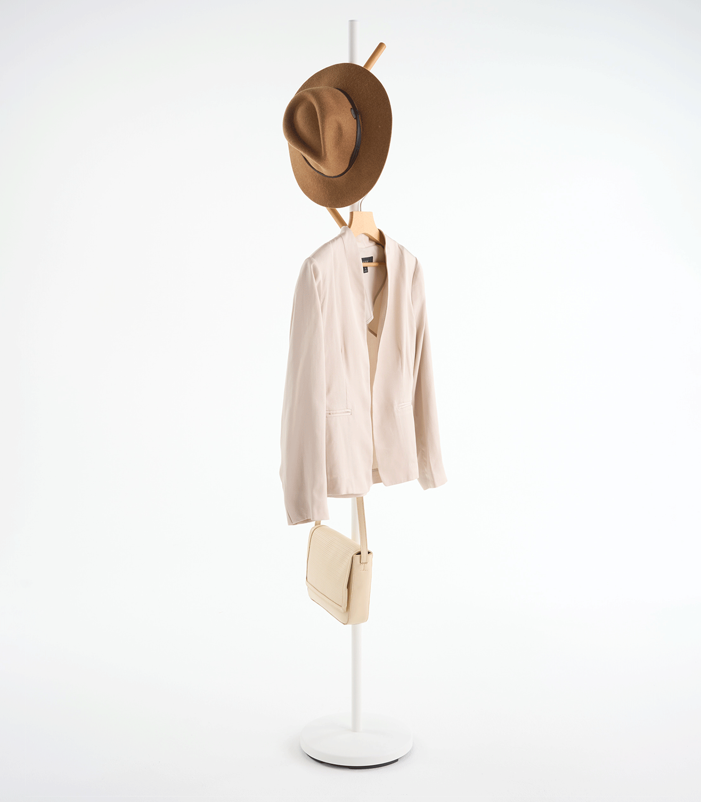 White Yamazaki Home Coat Rack (70" H) - Steel holding a brown hat near the top and a small cream shoulder bag on a lower branch, showing its tall, narrow profile.
