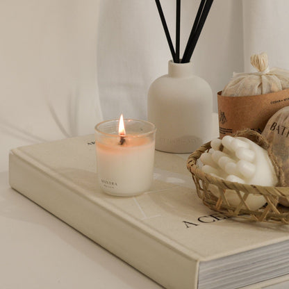 Candle burning on a book with a diffuser and basket of stones in the background