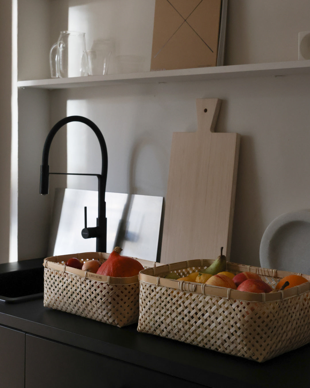 Rectangular bamboo baskets holding fresh produce on a dark kitchen counter.
