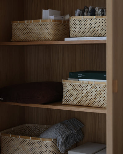 Closer view of rectangular bamboo baskets arranged across wooden shelves.