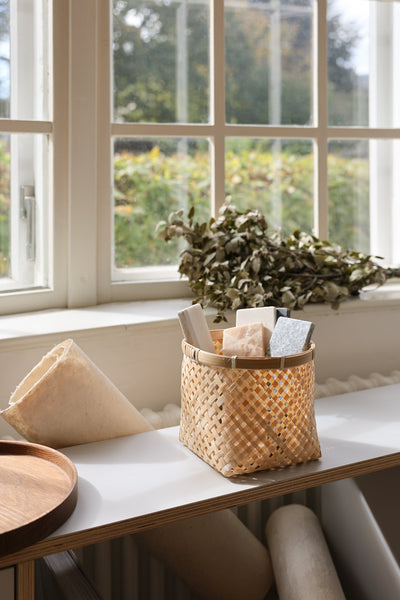 Muko basket holding papers and greenery on a table beside a bright window.