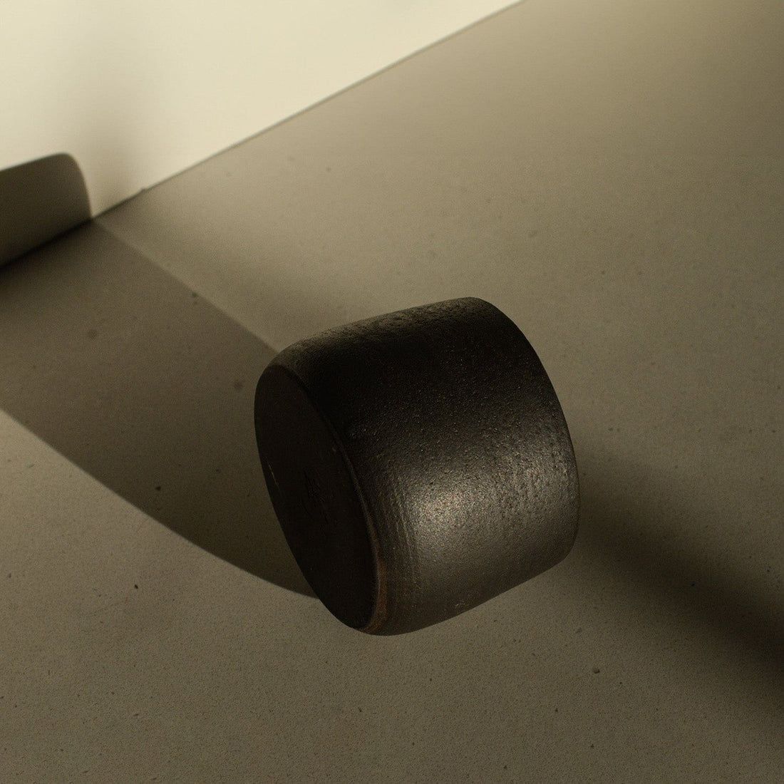 Black cylindrical object on a beige surface