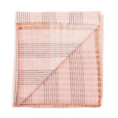 Folded blush-pink color variation of the Variously striped handwoven throw with fine woven lines and fringe