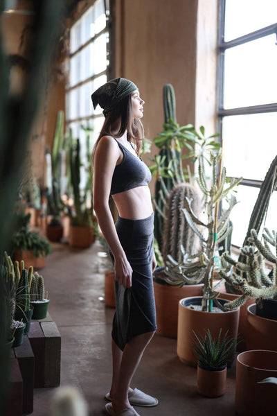 Woman wearing the convertible merino wool dress and skirt in a light-filled interior, showcasing versatile styling and natural wool comfort.