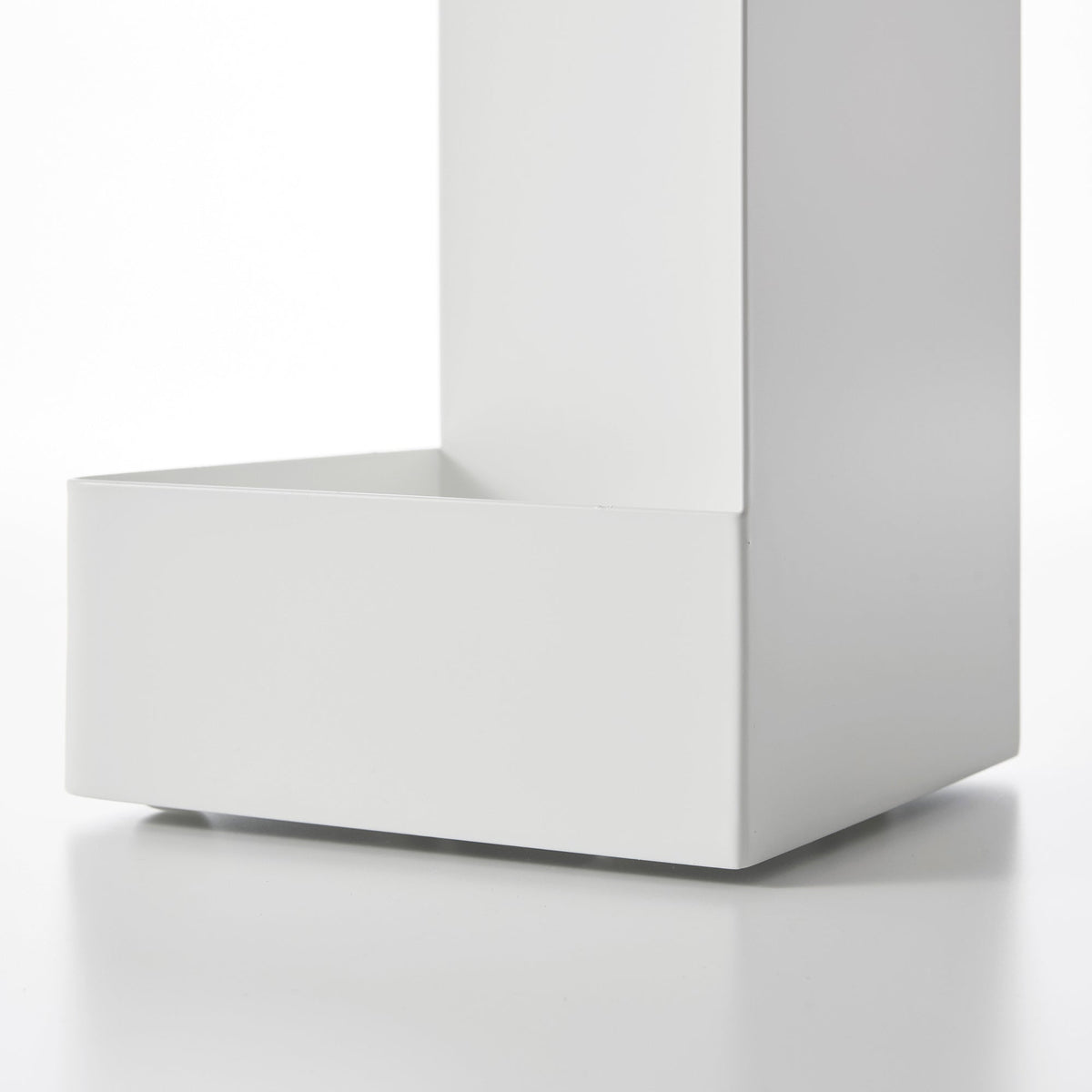 Close-up of the white Yamazaki Home Rolling Bathroom Organizer - Steel base, showing the deep rectangular lower tray, raised front edge and tall solid side panel.