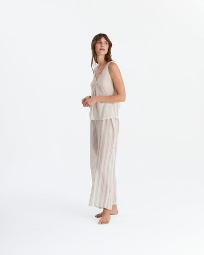 Angled view of the pajama set on a barefoot model, showing the loose sleeveless top and flowing striped pants.