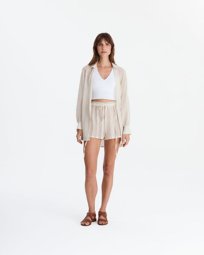 Full-length view of the cover-up worn open over a white crop top and matching drawstring shorts, with brown sandals.