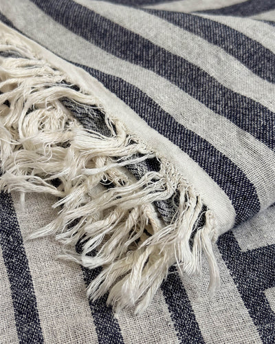 Angled close-up of the mattress pad’s quilted surface beneath a white pillow, with intersecting seams forming evenly spaced padded sections.