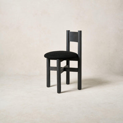 Angled view of Teddy dining chair highlighting black bouclé seat and oak frame