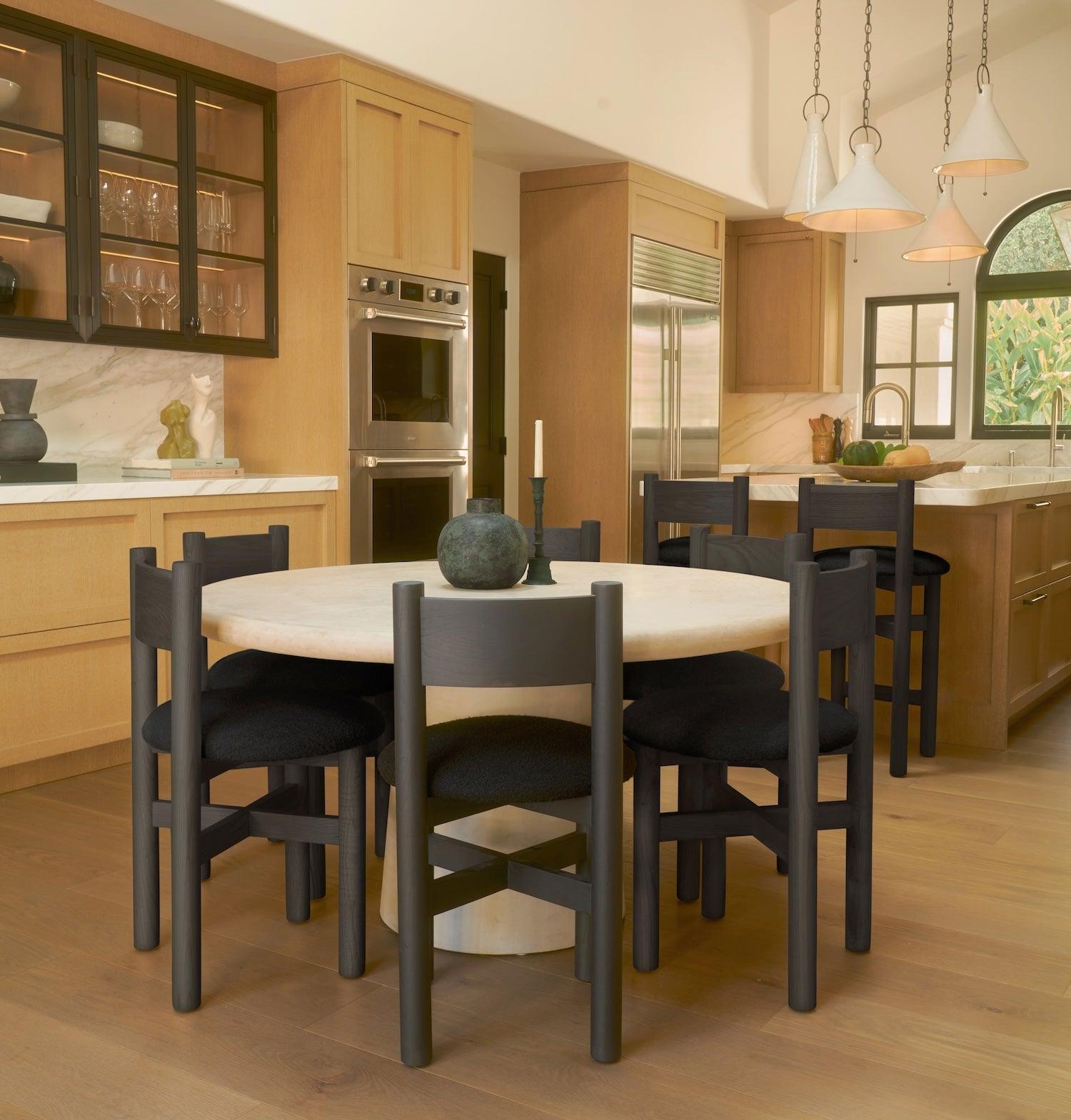 Teddy black dining chairs styled around round dining table in warm kitchen setting