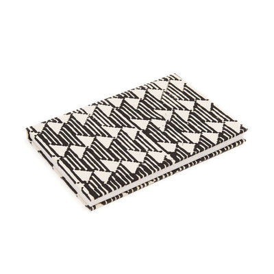 Angled product view of the closed Tria Black White journal showing its geometric cover, page edges and handcrafted binding