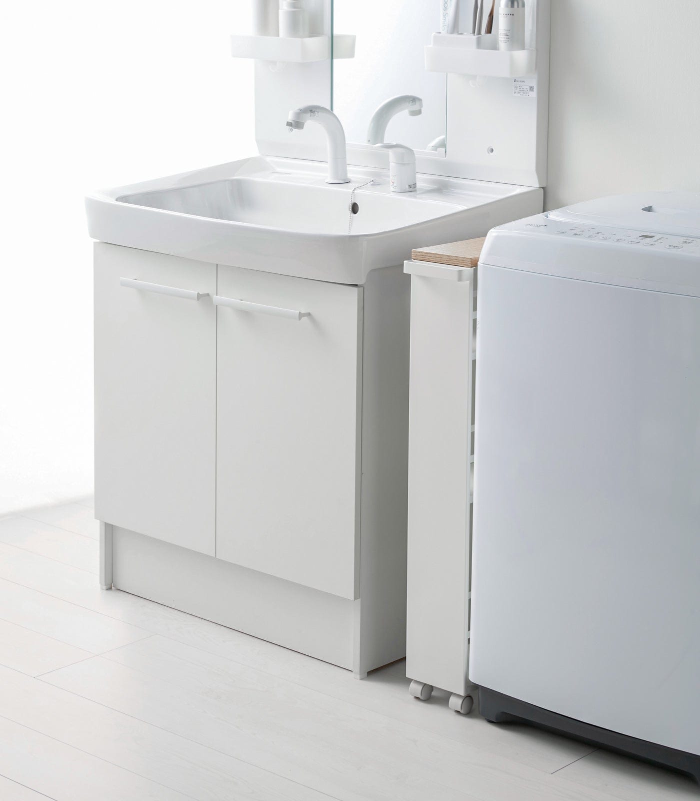 Bathroom setup with a white vanity unit, sink, and washing machine.