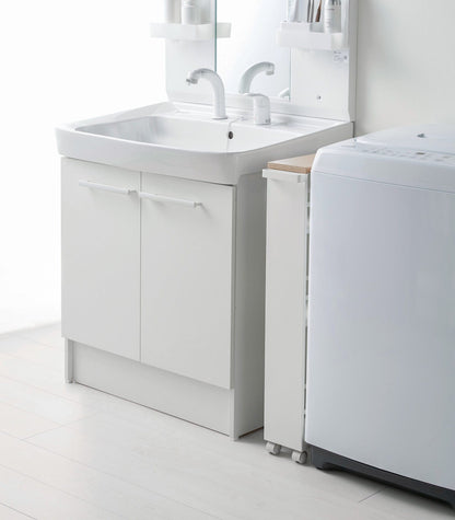Bathroom setup with a white vanity unit, sink, and washing machine.