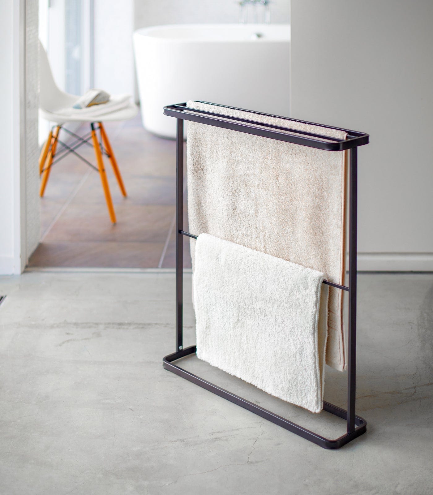 Towel rack with folded towels in a modern bathroom setting in Black