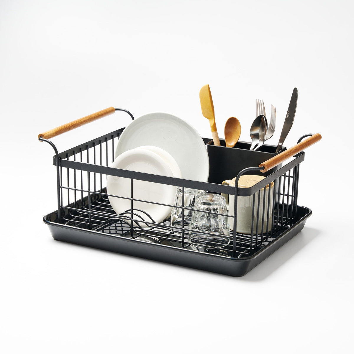 Black Yamazaki Home Dish Rack - Steel + Wood on white, with a rectangular wire basket, drip tray and light wood handles, holding upright plates, glasses, a mug and utensils in a divided caddy.