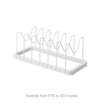 Empty white Yamazaki Home Adjustable Pot Lid Organizer - Steel shown at an angle, with a rectangular open base and a row of tall wire dividers with central dips.