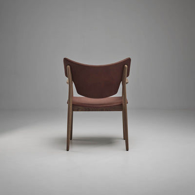 Rear view of the reddish-brown Eikund Veng Arm Chair, showing its upholstered back between dark wood supports and the matching seat below.