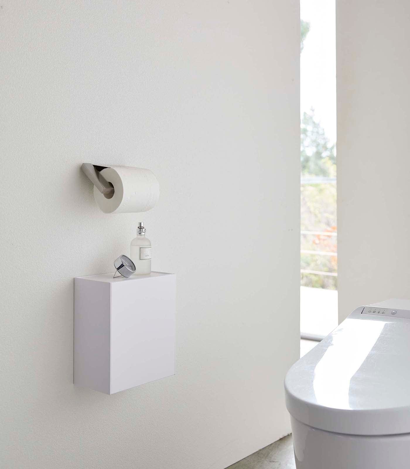 Modern bathroom with a toilet and wall-mounted cabinet. Wall-Mounted Storage or Trash Bin shown on wall.