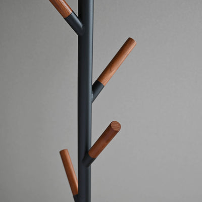 Detail of the black Yamazaki Home Coat Rack (70" H) - Steel branches, showing upward-angled supports capped with cylindrical brown wood tips.