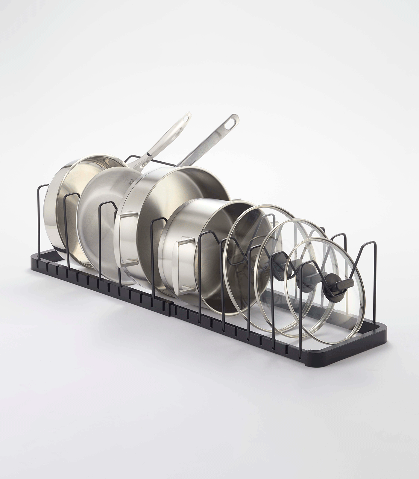 Black Yamazaki Home Adjustable Pot Lid Organizer - Steel fitted lengthwise inside an open kitchen drawer, with pans and lids arranged beside storage canisters.