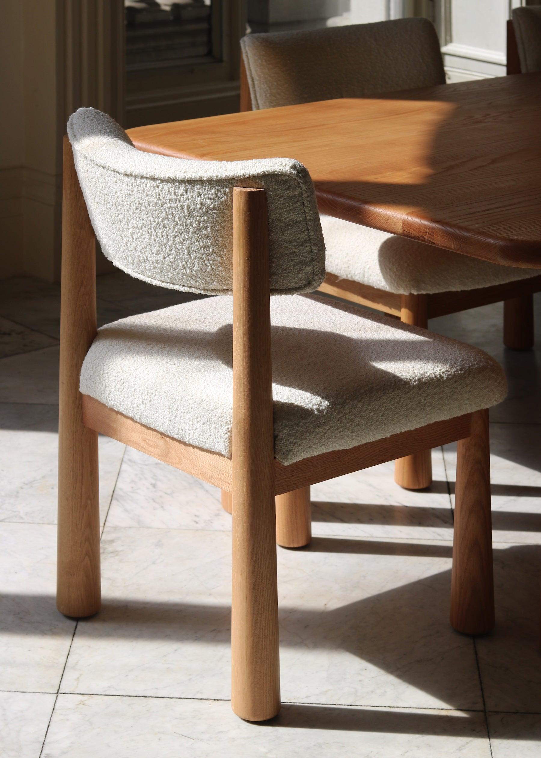 Charlie dining chair in white oak with bouclé upholstery, angled dining table view