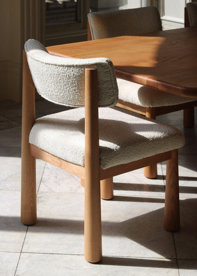 Charlie dining chair in white oak with bouclé upholstery, angled dining table view