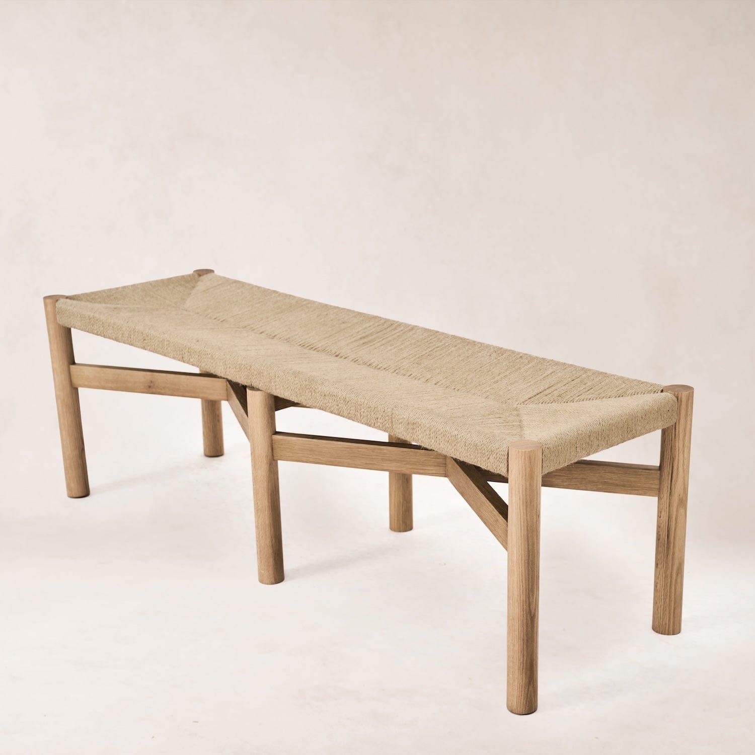 Angled view of Nonna bench showing woven seat and oak legs