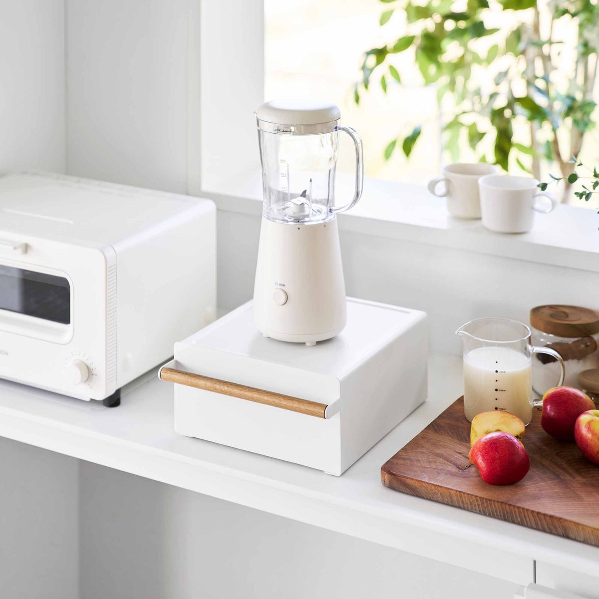 Yamazaki Home Countertop Rack with Drawer - Steel + Wood used beneath a compact white blender, with the drawer closed beside fruit and a drink on a wooden board.